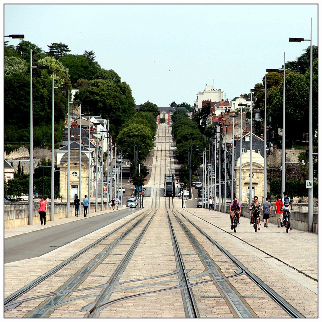 Vue du pont Wilson à Tours : les voies du tramway au centre, une voie entrante pour les motorisés à gauche et une aire piétonne à droite. Au second plan, la Tranchée qui monte sur le coteau nord de la Loire.